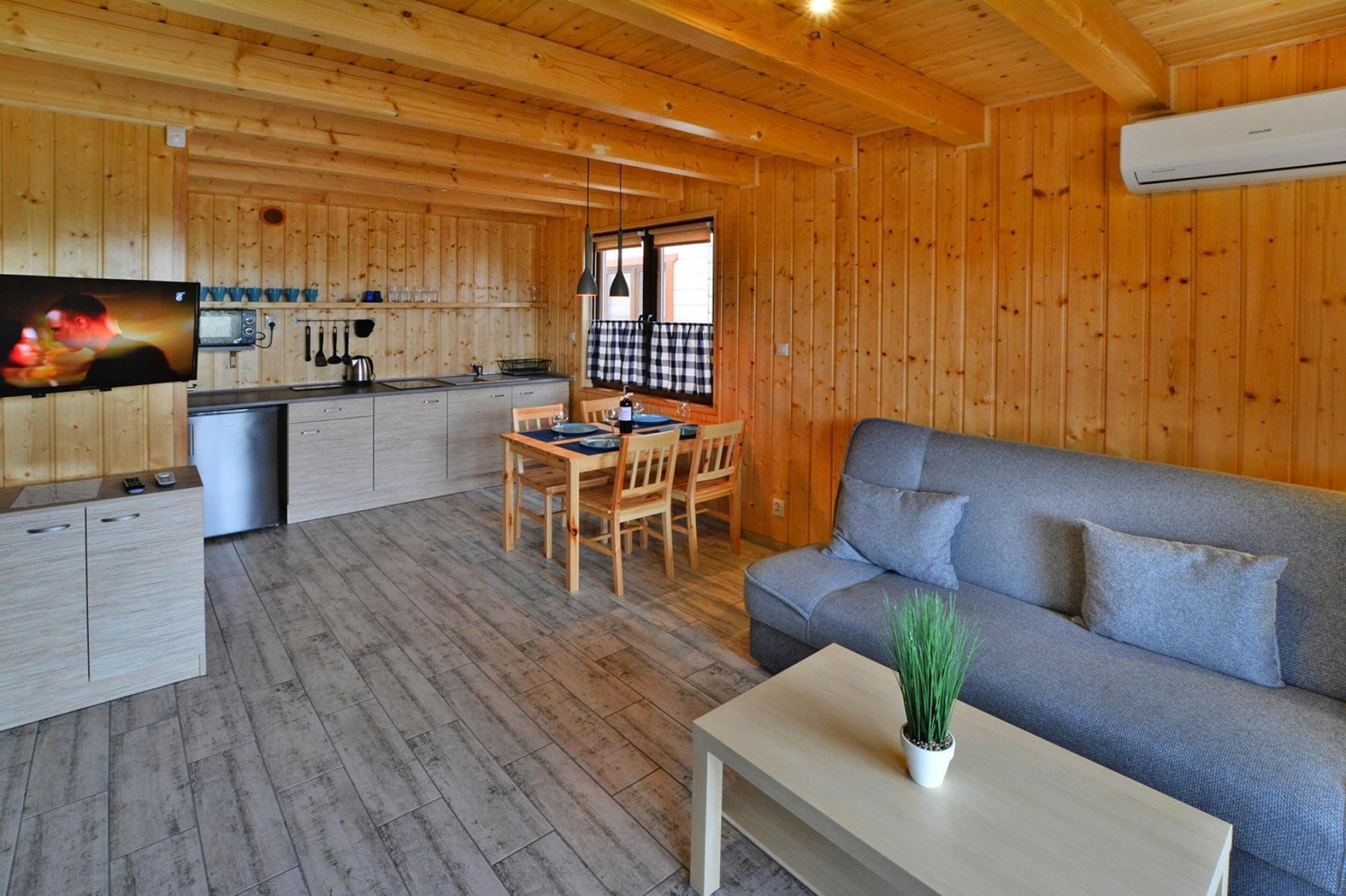 A wooden cabin interior with a dining area, sofa, and kitchen.