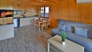 A wooden cabin interior with a dining area, sofa, and kitchen. - Holiday Home in Sianozety Near Beach (Ustronie Morskie)
