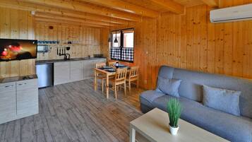 A wooden cabin interior with a dining area, sofa, and kitchen.
