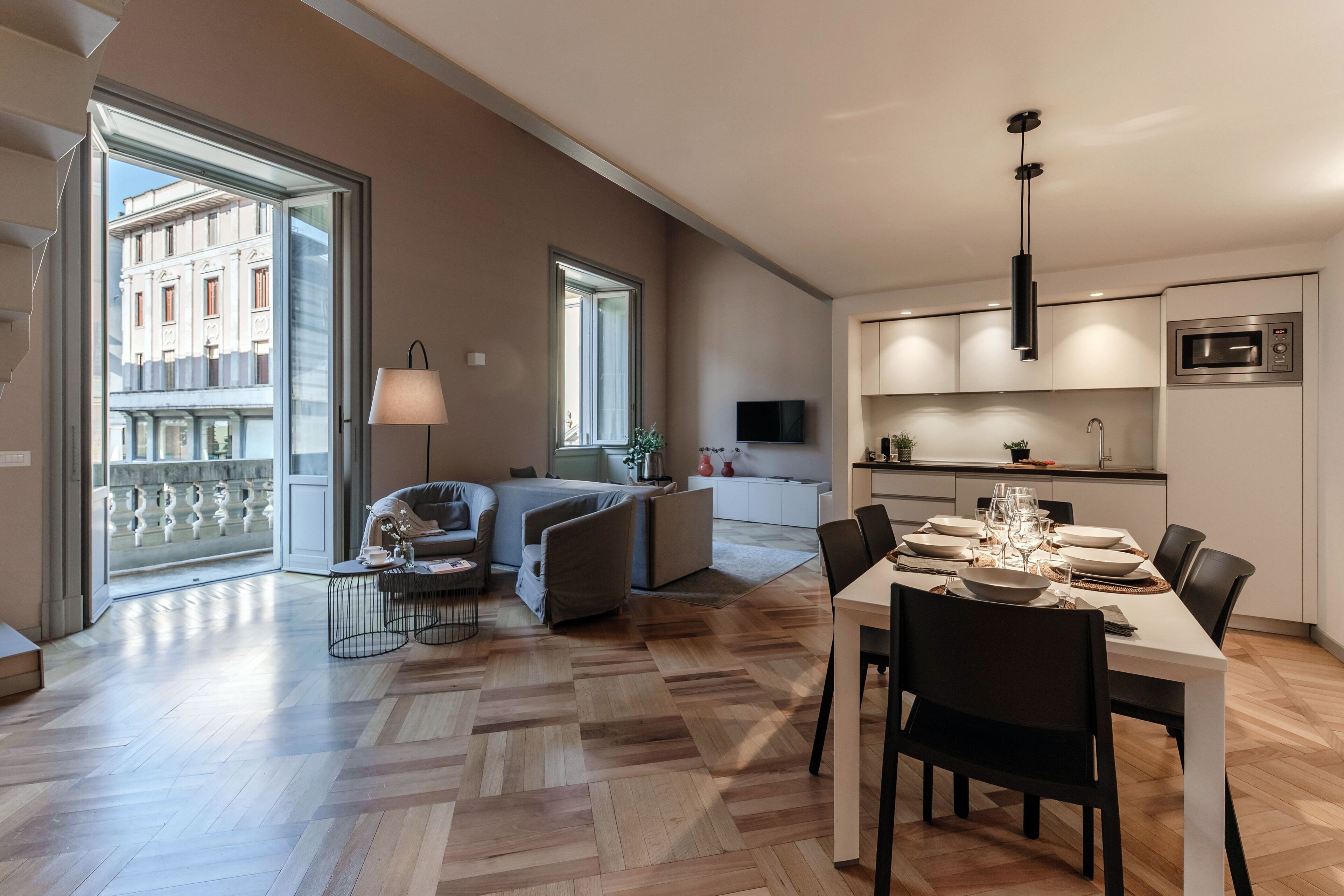 Un apartamento moderno con comedor, un conjunto de sofás, televisor y cocina.