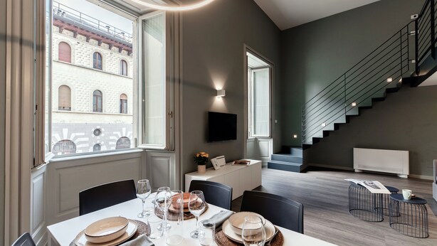 Ein Essbereich mit einem Tisch für vier Personen, einer Treppe und Blick auf ein Gebäude.