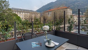 Ein Balkon mit Tisch, Blumen in einer Vase und einem Brillenpaar.
