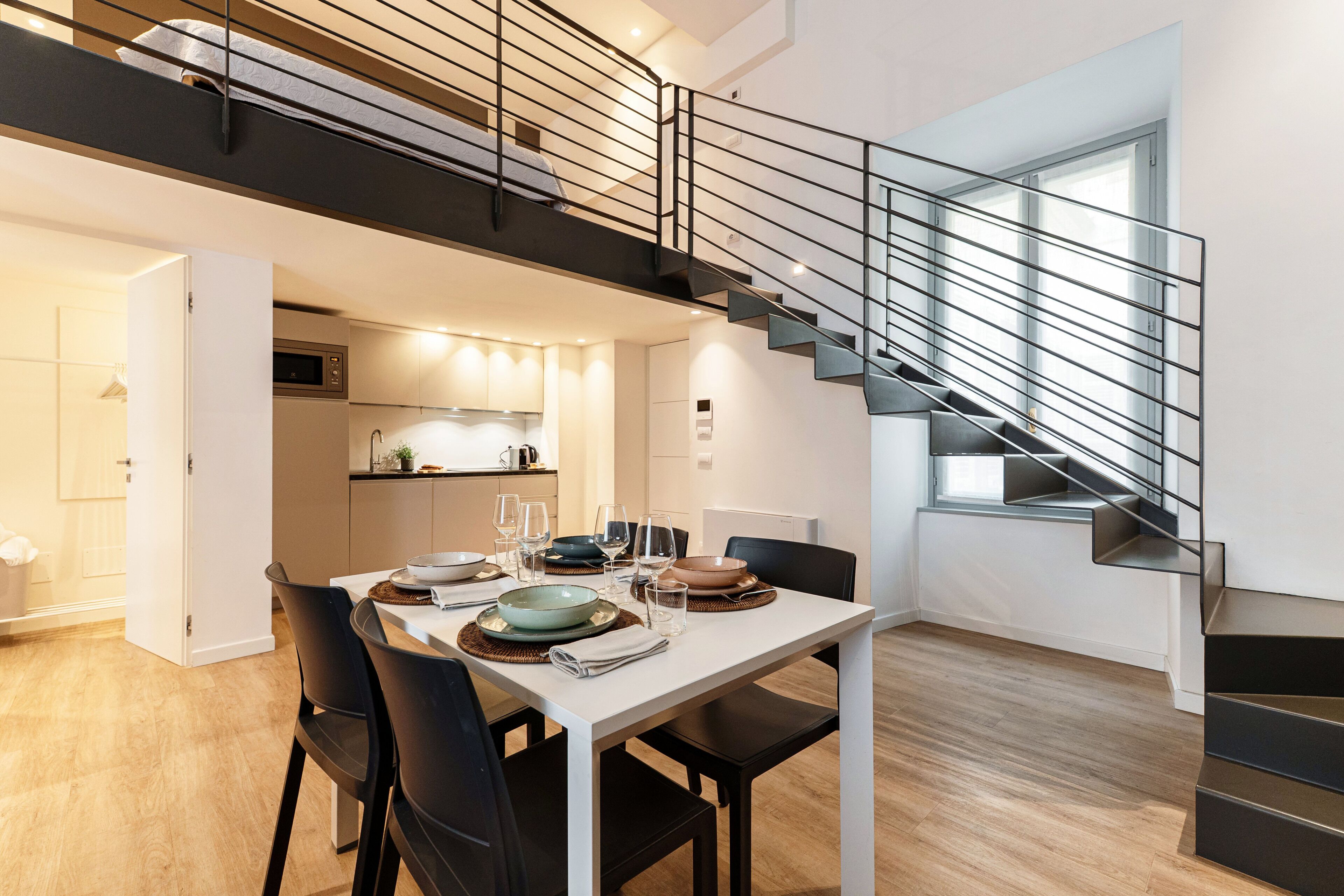 A modern interior with a dining area, kitchen, and staircase.