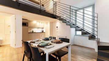 A modern interior with a dining area, kitchen, and staircase.