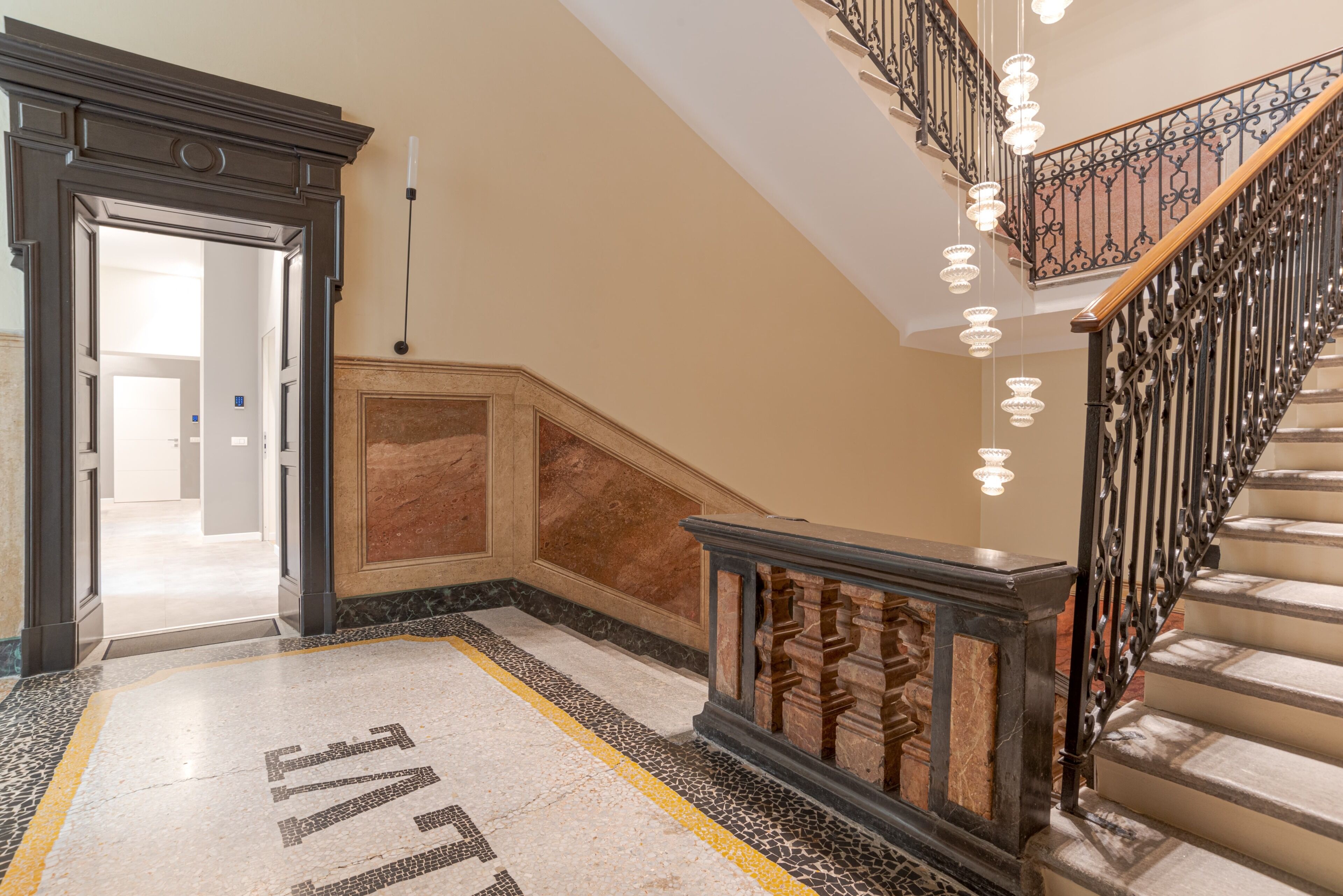 A grand staircase with a marble floor and a handrail, leading to an upper level.