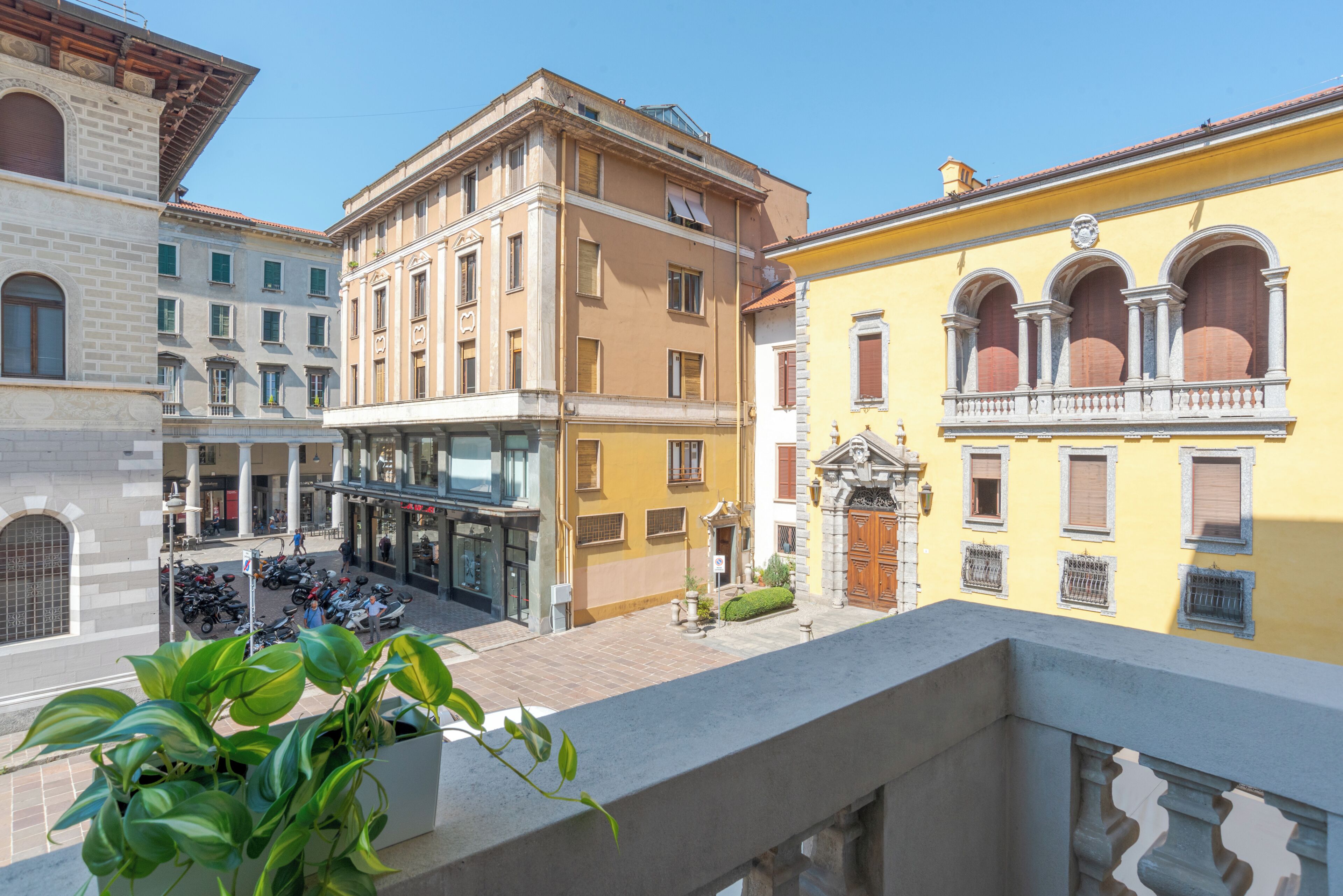 A courtyard with buildings, a balcony, and a potted plant.
