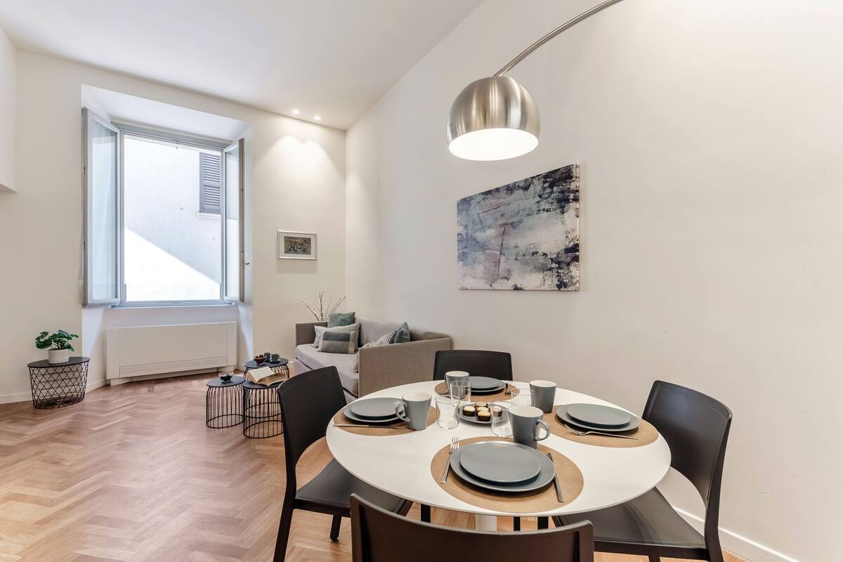 A dining area with a round table, chairs, and a pendant light.