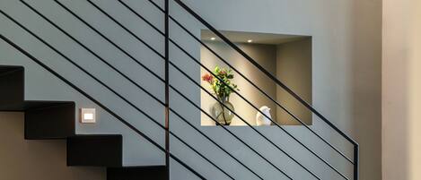 A modern staircase with a minimalist design, featuring a glass enclosure at the top.