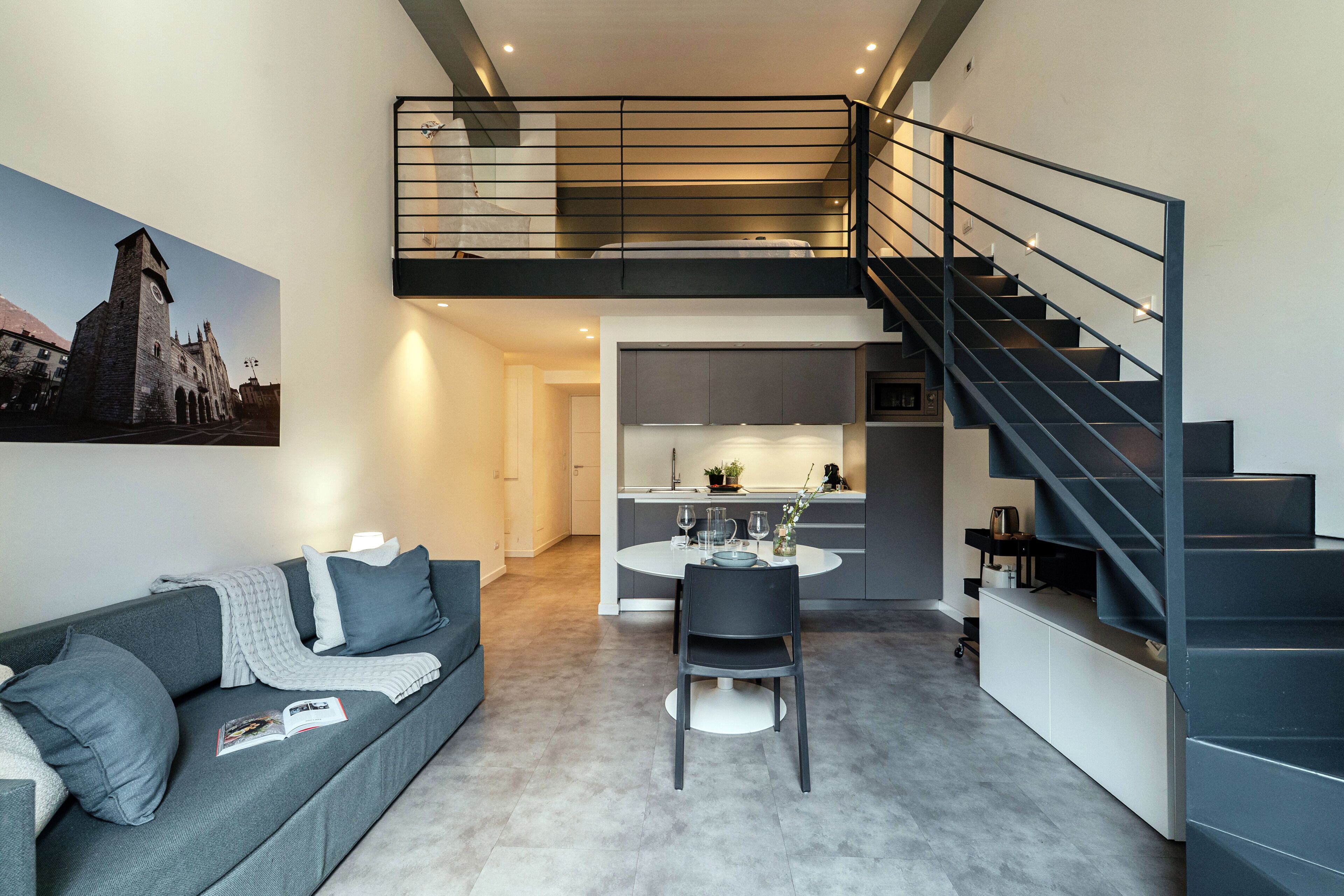 Un apartamento moderno con comedor, cocina y una escalera a un nivel superior.