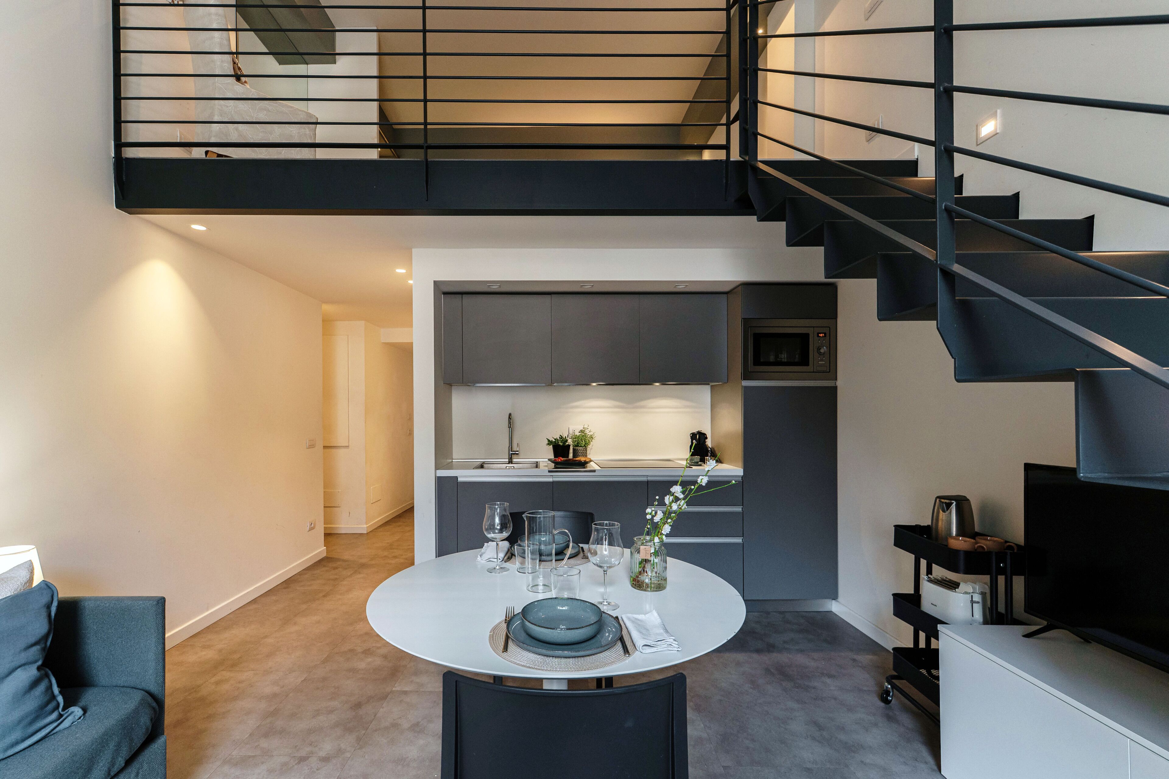 A modern interior with a dining area, kitchen, and a staircase.