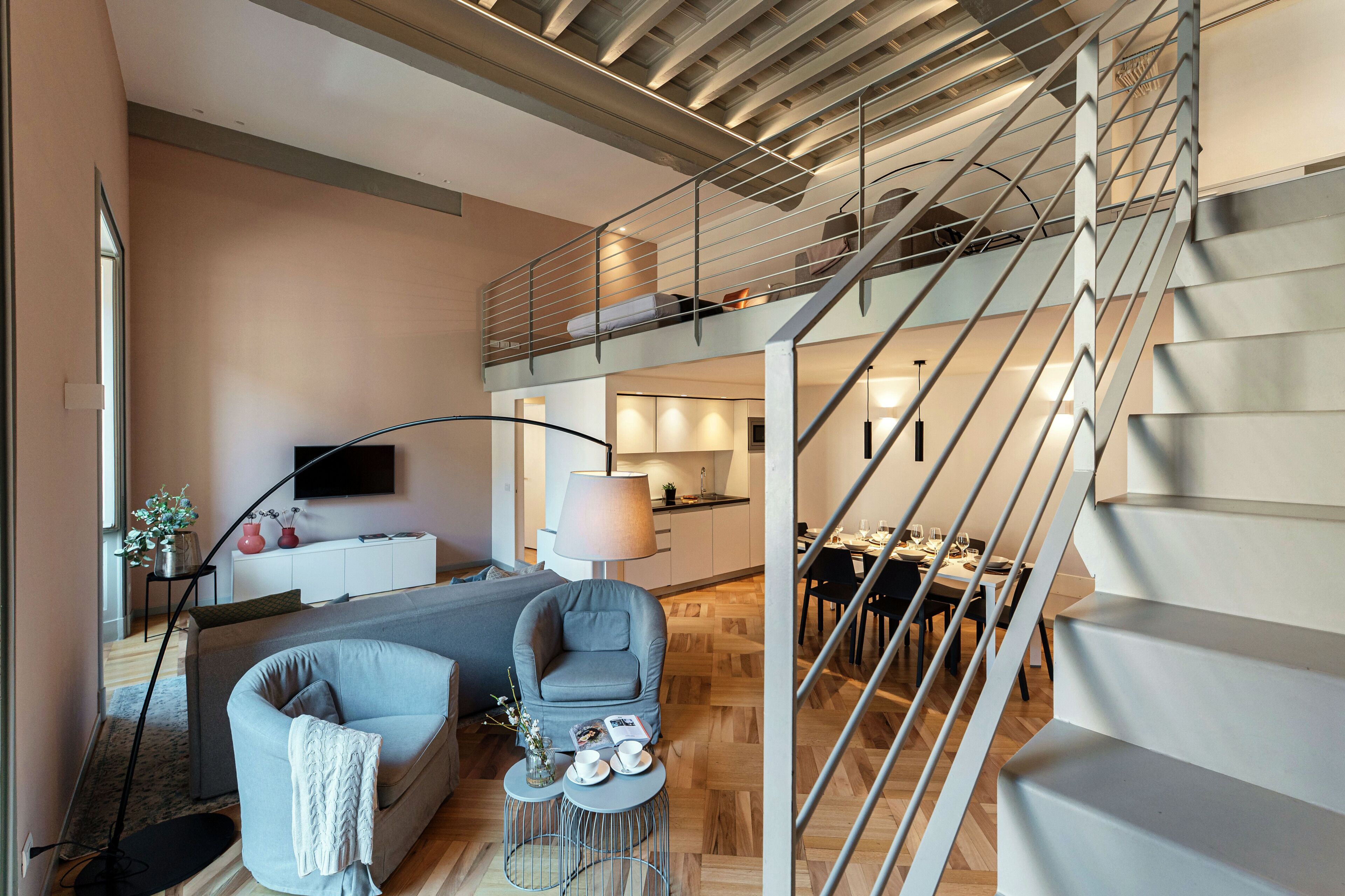 Un espace de vie moderne comprenant un escalier, un canapé, un coin repas et une cuisine.