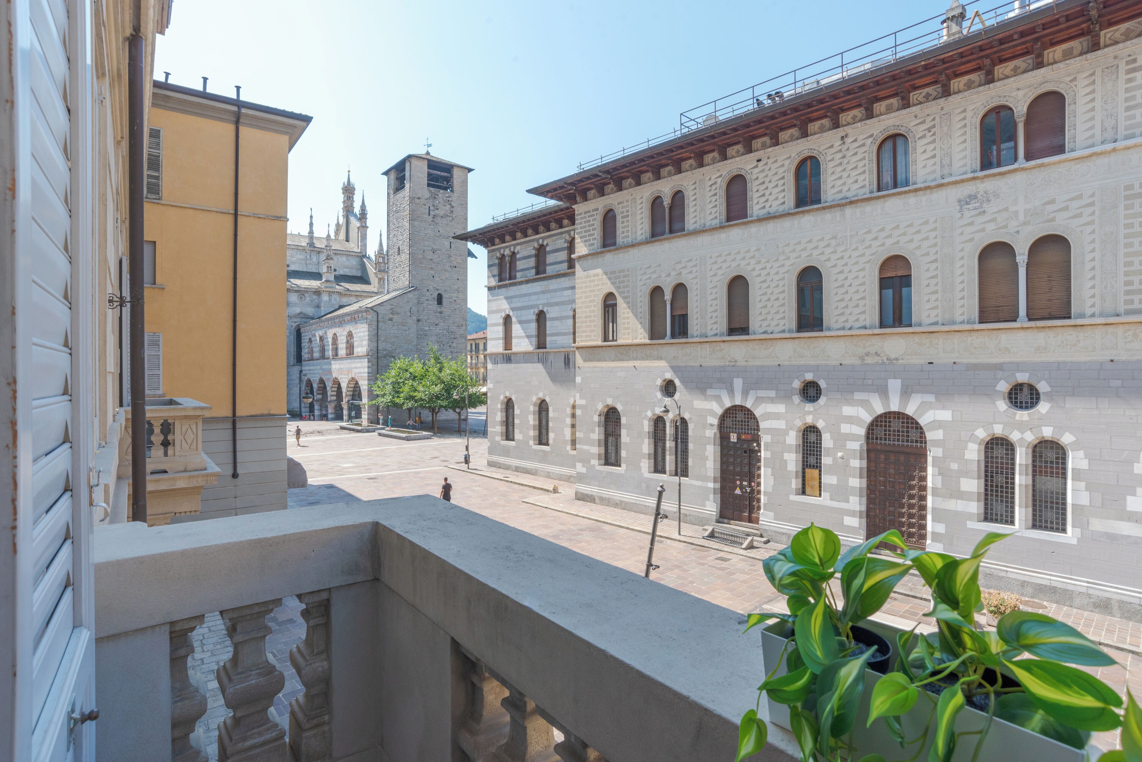 Un cortile con un edificio caratterizzato da finestre ad arco e una torre.