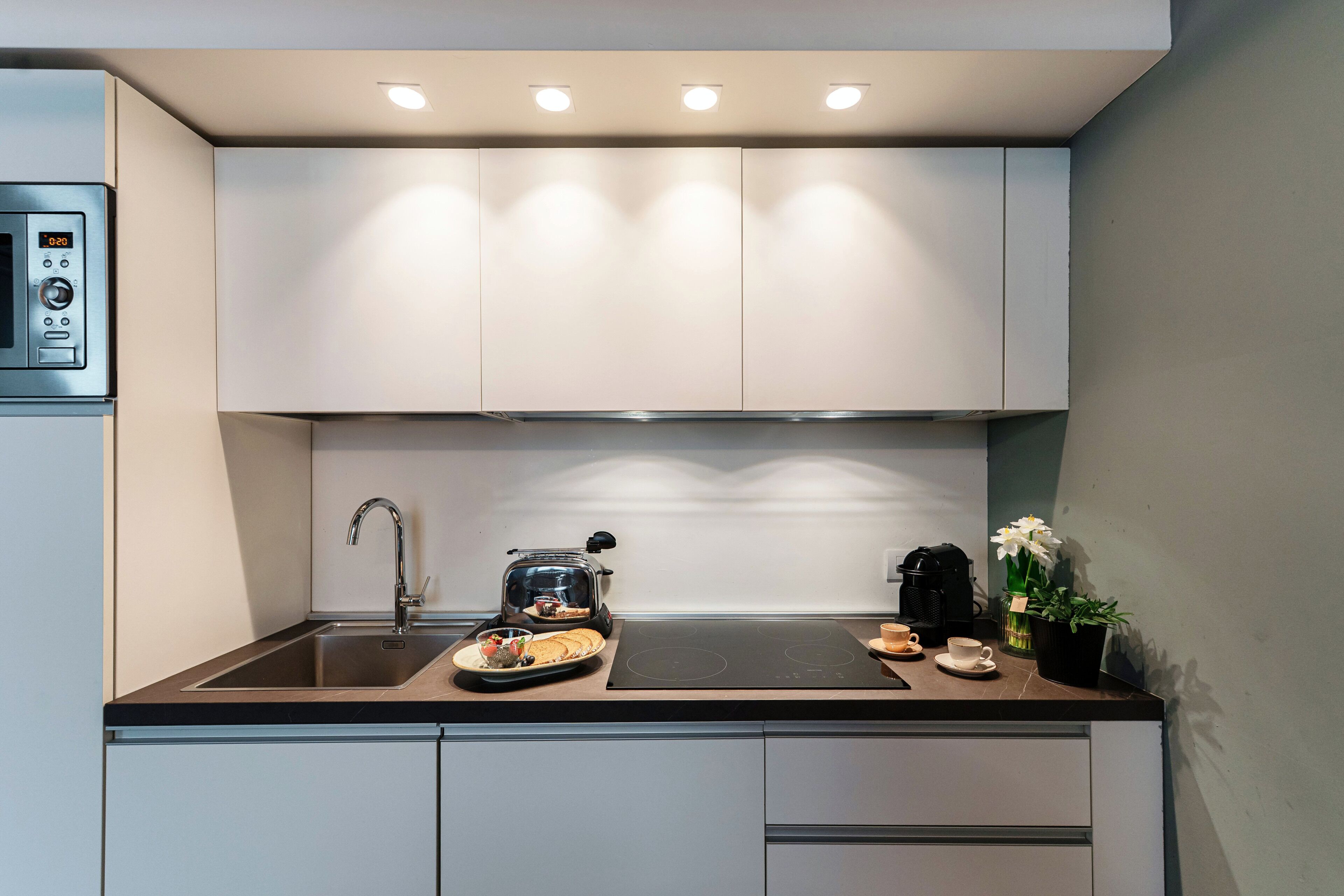 A modern kitchen with a built-in oven, a coffee maker, and a sink.