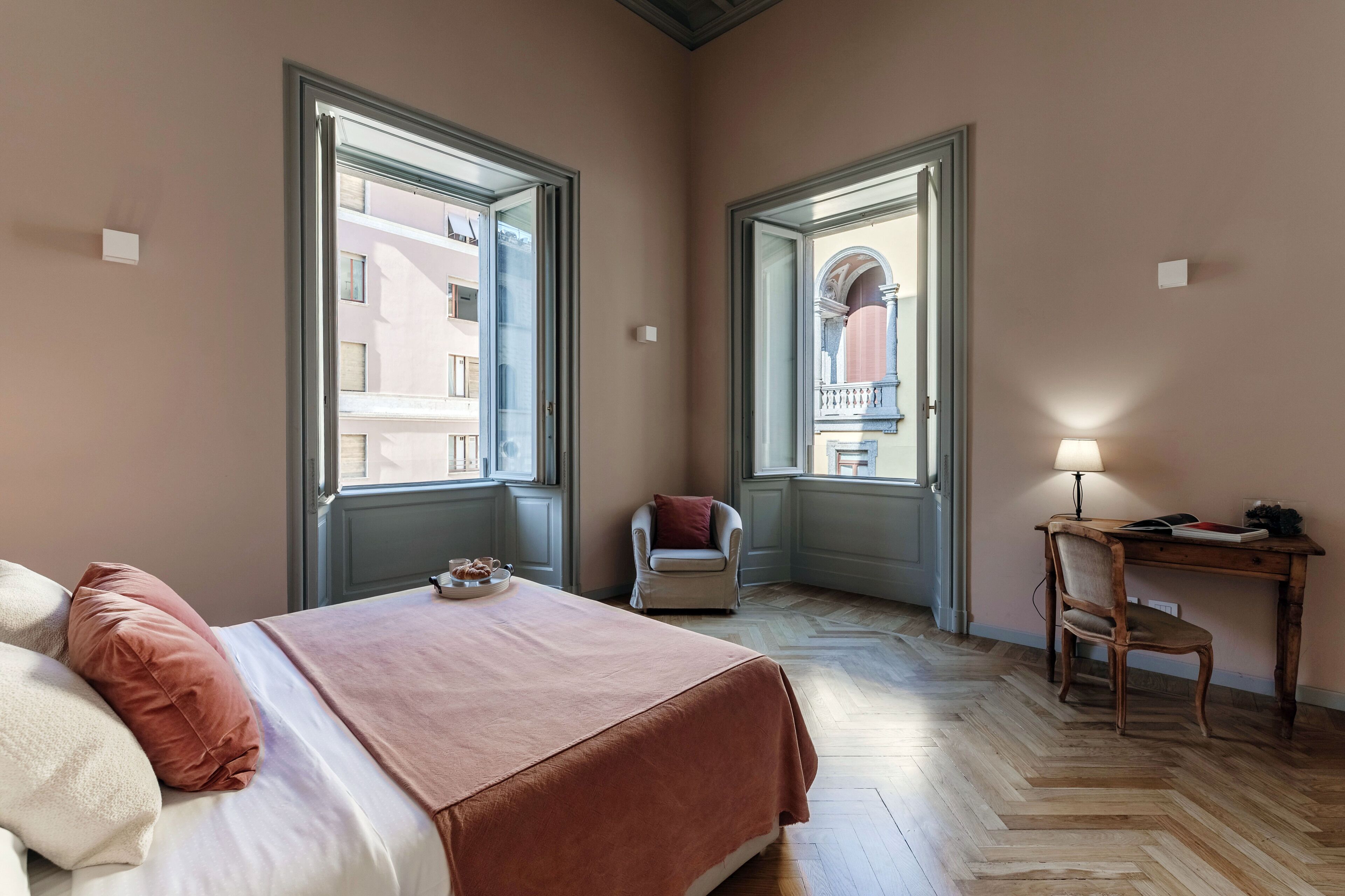 Une chambre à coucher avec un lit, une chaise, un bureau et de grandes fenêtres.