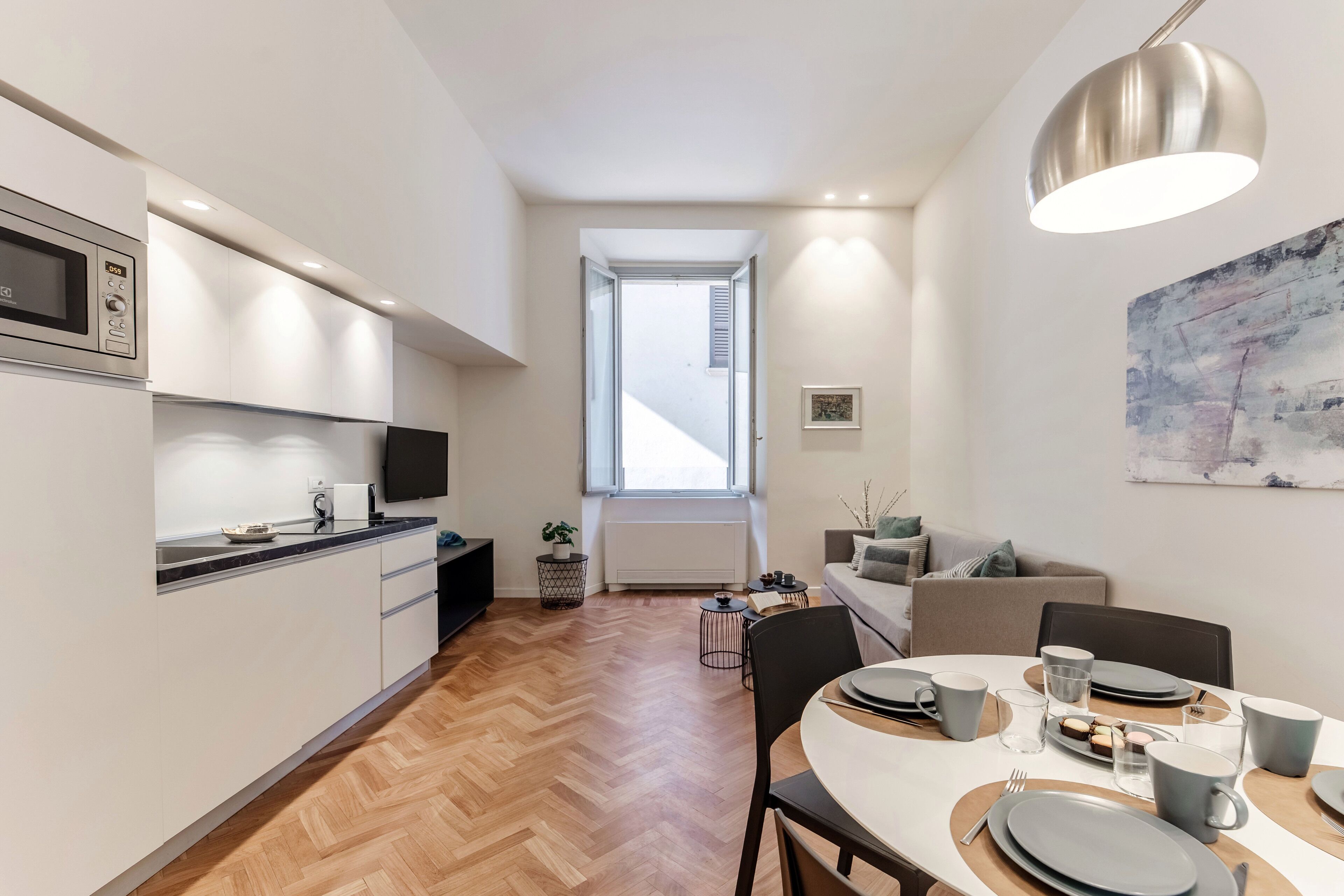 A modern kitchen with a microwave, stove, and dining area with a table set for two.