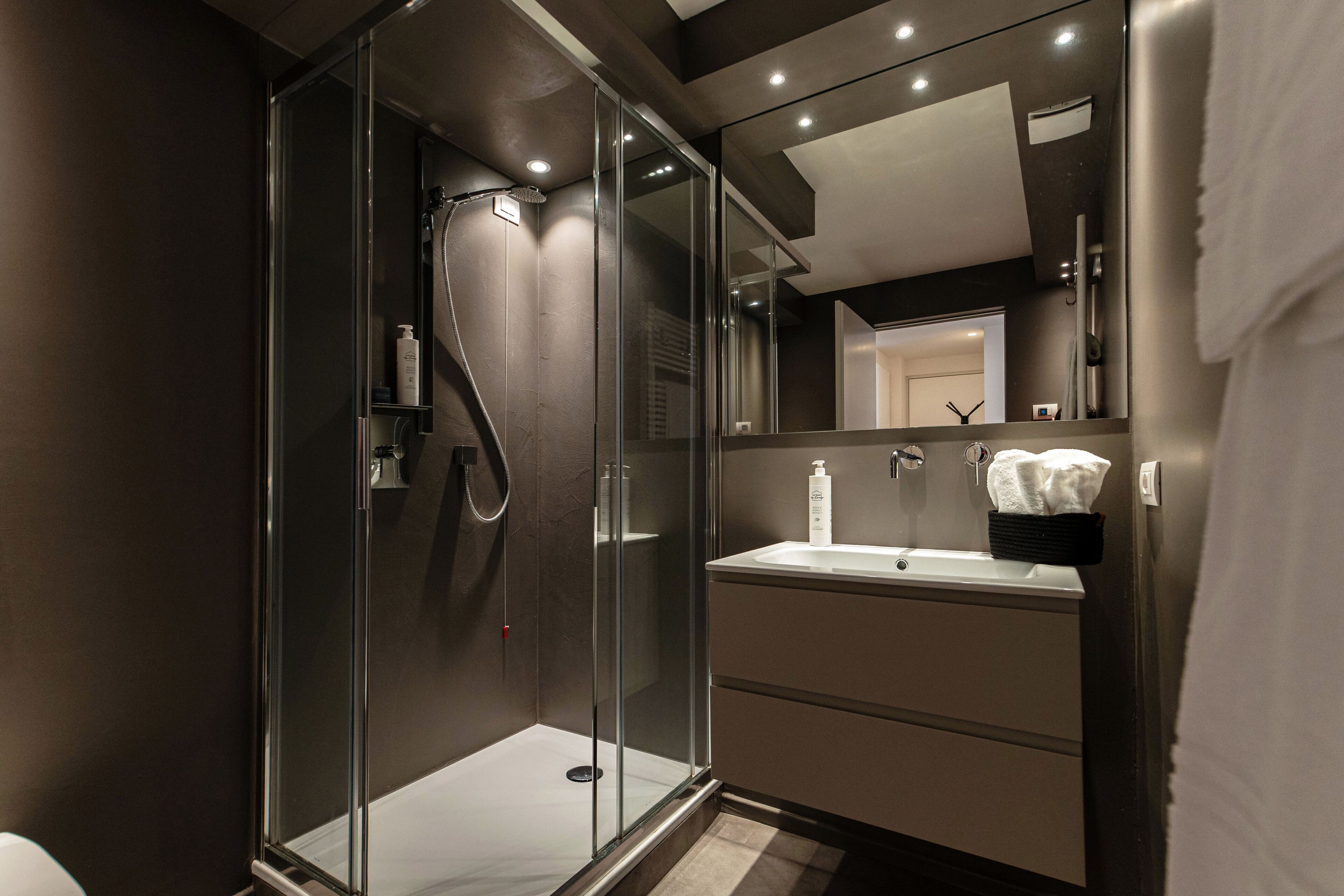 A modern bathroom with a glass-enclosed shower, a sink, and a mirror.