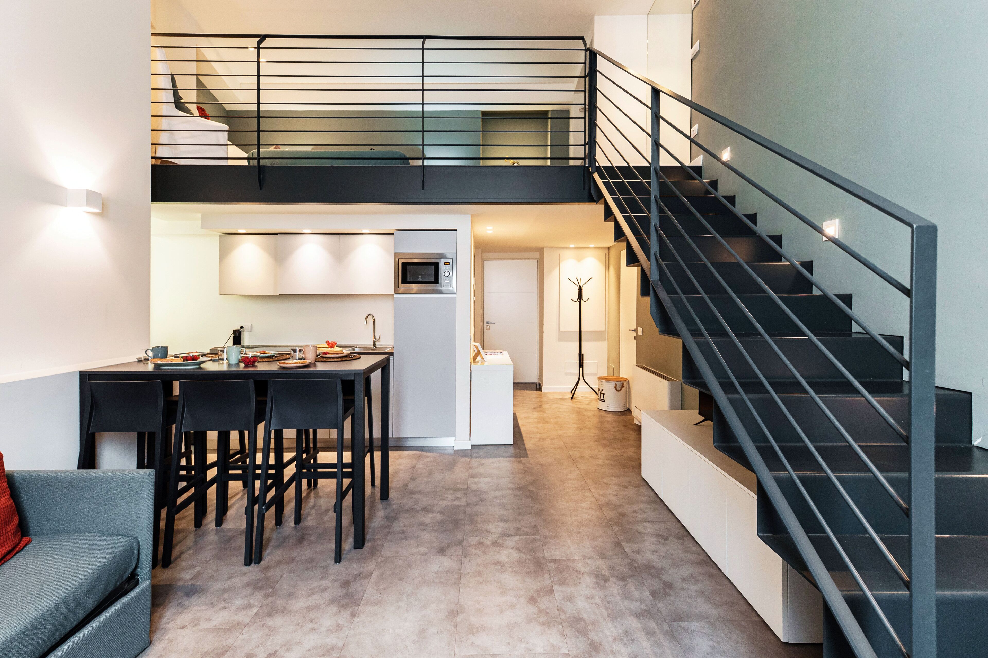 Un interior moderno con comedor, cocina y escalera.