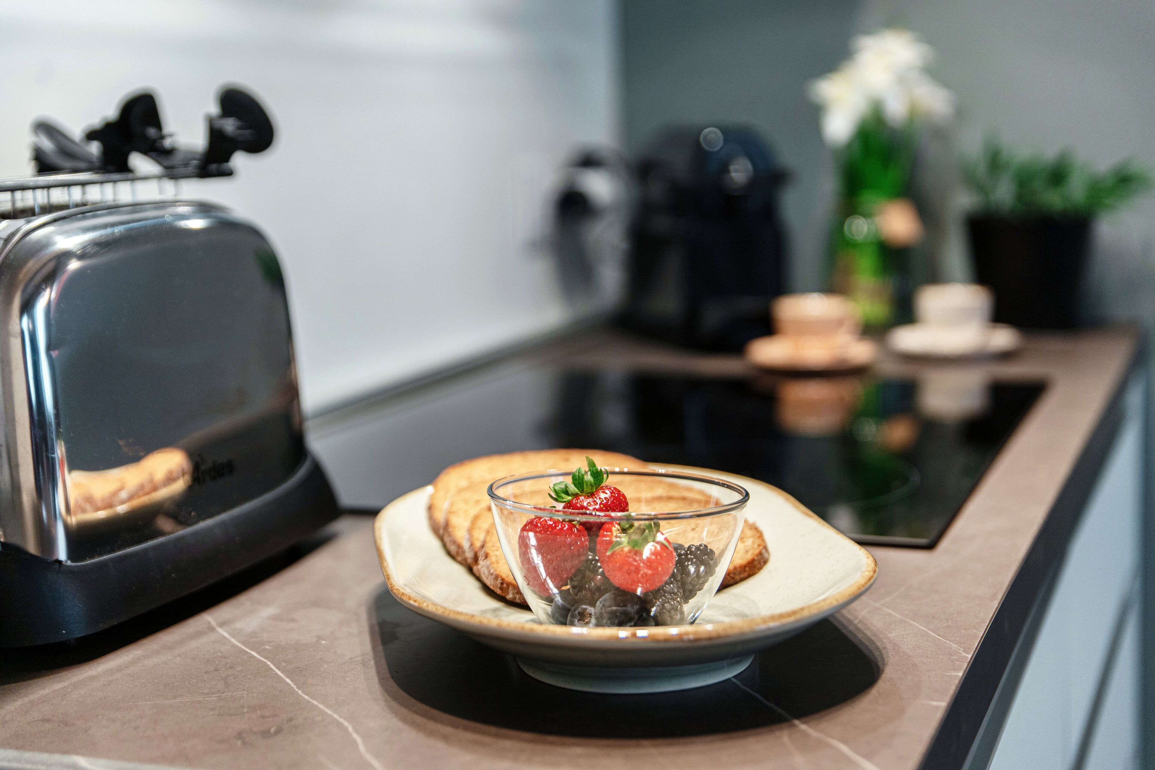 A kitchen with a toaster, a plate with toast and berries, and a coffee maker.