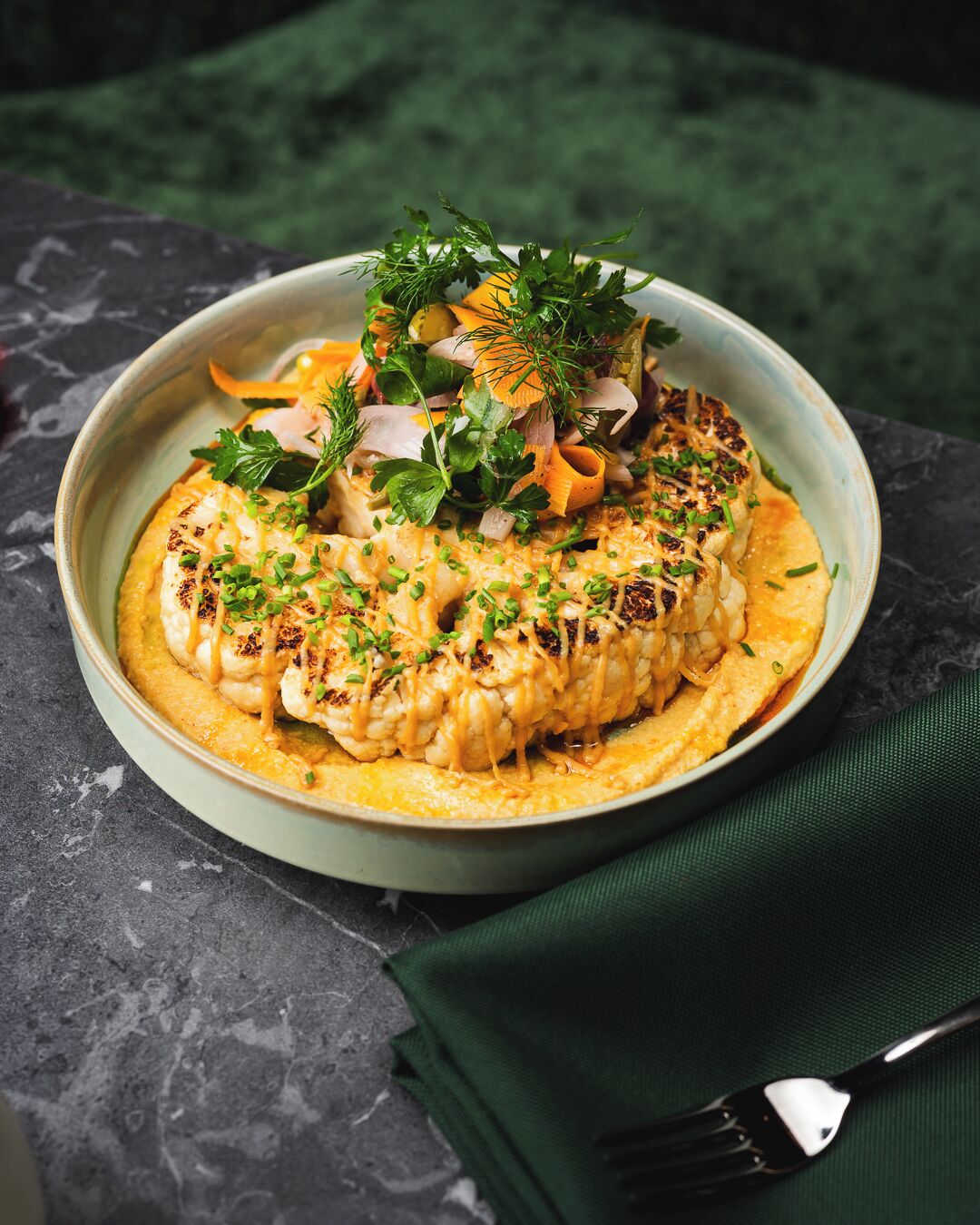 A plate of food with grilled chicken, vegetables, and a creamy sauce, garnished with herbs.