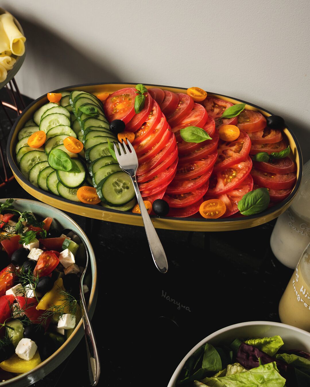 A salad with cucumbers, tomatoes, and olives on a plate.