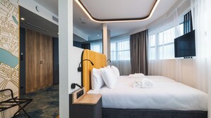A hotel room with a bed, a wooden headboard, a flat-screen TV, and a large window with curtains. - Focus Hotel Premium Wrocław (Wroclaw)
