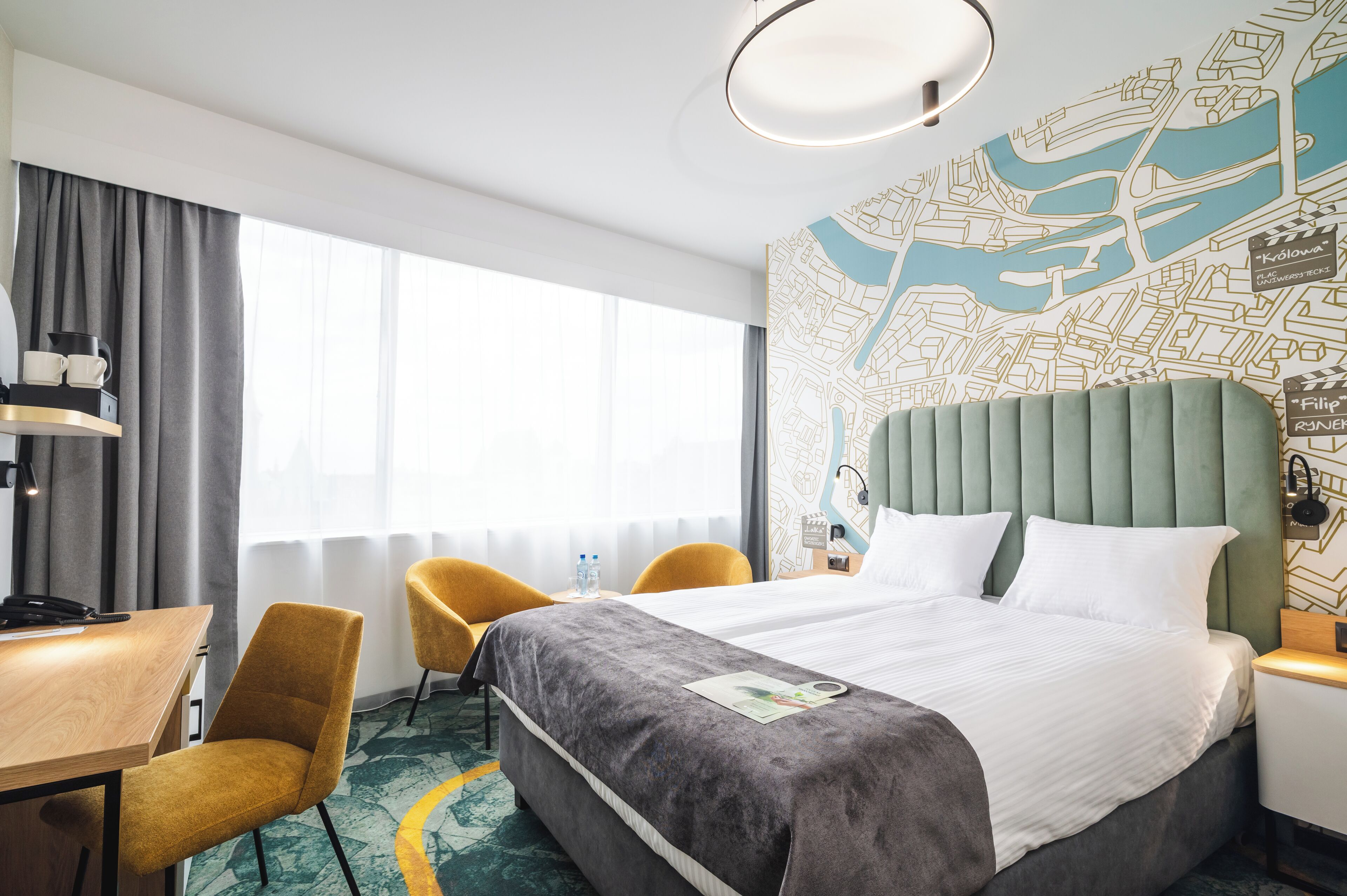 Une chambre d’hôtel avec un grand lit, deux chaises, un bureau et une carte accrochée au mur.