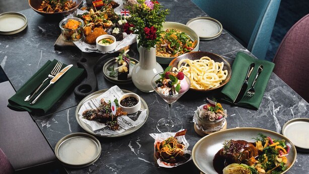 A dining table set with various dishes, a vase with flowers, and a wooden serving board. - Focus Hotel Premium Wrocław (Wroclaw)