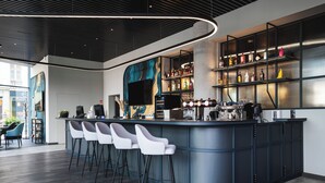 A modern bar area with a curved counter, bar stools, and a variety of liquor bottles. - Focus Hotel Premium Wrocław (Wroclaw)