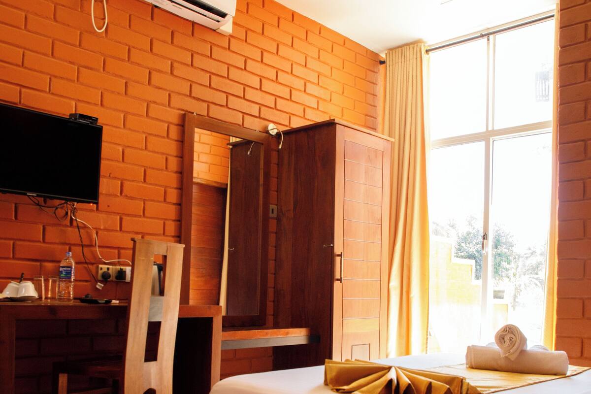 Habitación de hotel con dos camas, un escritorio, una silla, un armario y un equipo de aire acondicionado.