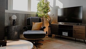 A modern living room with a large TV, a comfortable sofa, a coffee table, and a potted plant. - Modern Industrial Loft for Two (Benton Harbor)