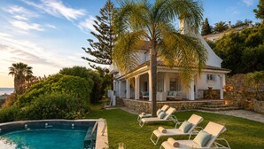A pool with lounge chairs, a covered patio, and a view of a white house with stone walls. - Recently renovated villa overlooking the coast of Atlanterra, for 8 pax. (Tarifa)