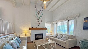 A spacious living room with a fireplace, a sofa set, a coffee table, and a view of the ocean through large windows. - Recently renovated villa overlooking the coast of Atlanterra, for 8 pax. (Tarifa)