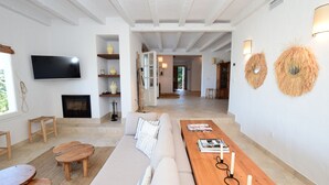 A modern living room with a sofa, coffee table, and TV. There are wooden stools and a fireplace.