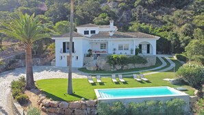 A white villa with a swimming pool, stone steps, and a well-maintained lawn.