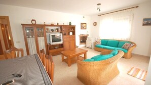 Un salon comprenant un canapé, un téléviseur, un meuble et une table à manger.