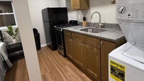 A compact kitchen with wooden cabinets, a built-in stove, and a washing machine.