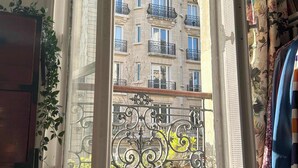 A room with a large window overlooking a multi-story building with balconies. - Carreau du Temple Marais CityCosy (Paris)