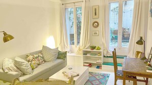A cozy living room with a sofa, a coffee table, a bookshelf, and a dining area with a chair. - Carreau du Temple Marais CityCosy (Paris)