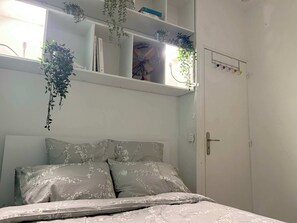Une chambre à coucher avec un lit, une étagère avec des plantes et une armoire.