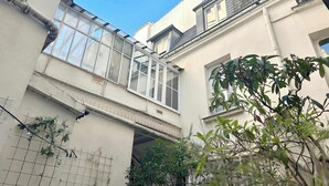 A narrow alleyway with a metal staircase leading to a building with a glass facade. - Carreau du Temple Marais CityCosy (Paris)