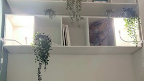 A bedroom with a bed, pillows, a ceiling fan, and shelves with plants and books. - Carreau du Temple Marais CityCosy (Paris)