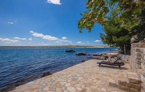 A stone-paved area with a lounge chair and a small dock with boats. - Villa Sadic Nearby Zadar - Crovillas (Posedarje)