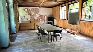 A spacious room with a large wooden table, chairs, a chalkboard, and a television.