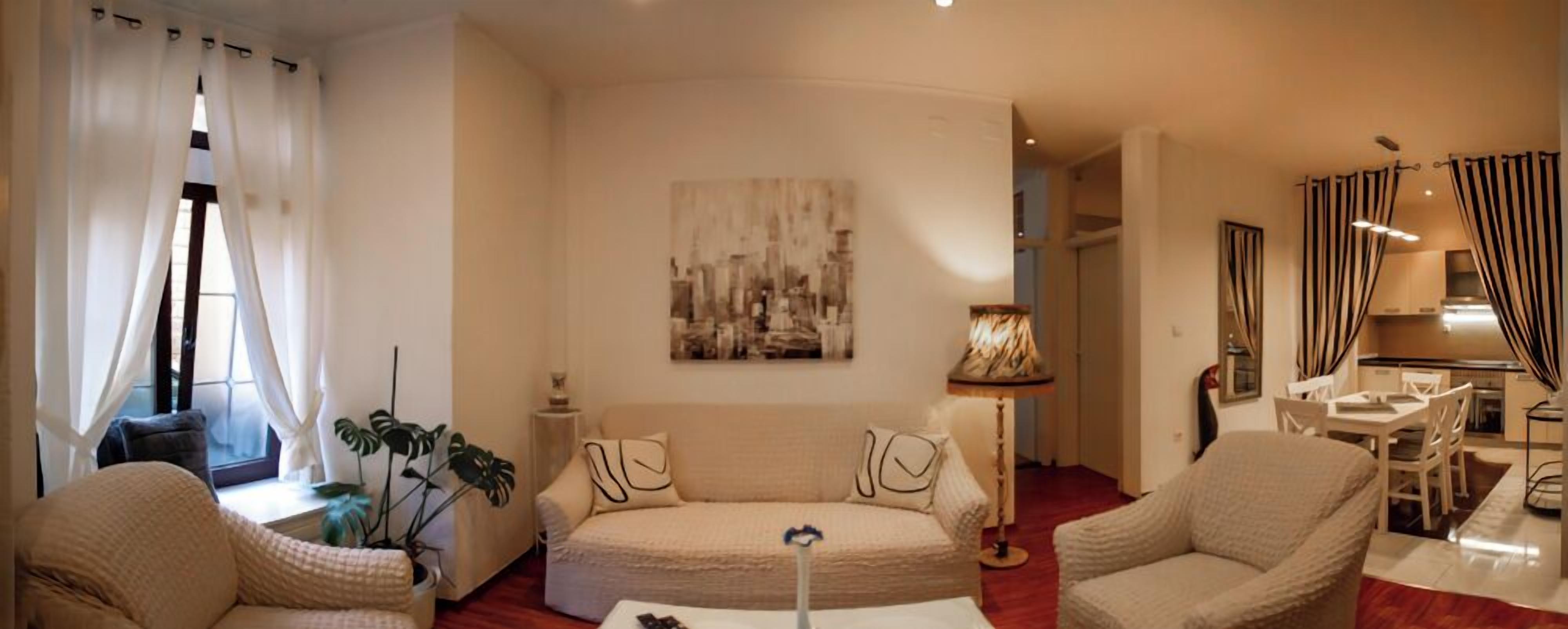 A living room with a sofa, armchairs, a coffee table, and a painting on the wall.