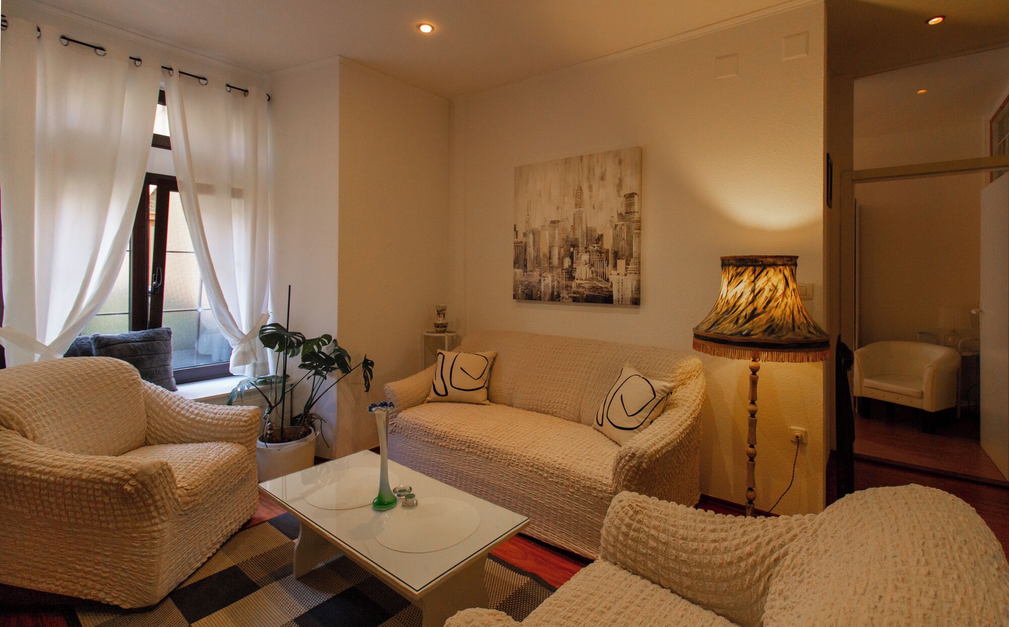 A cozy living room with a sofa, armchairs, a coffee table, and a lamp.