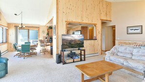 Ein geräumiges Wohnzimmer mit großem Flachbildfernseher, Holzwänden, einer Couch und einem Couchtisch.