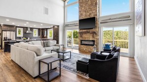 A spacious living area with a fireplace, large windows, and a balcony. - Van Kirk Cove 6 BDR Stunner! (Branson West)