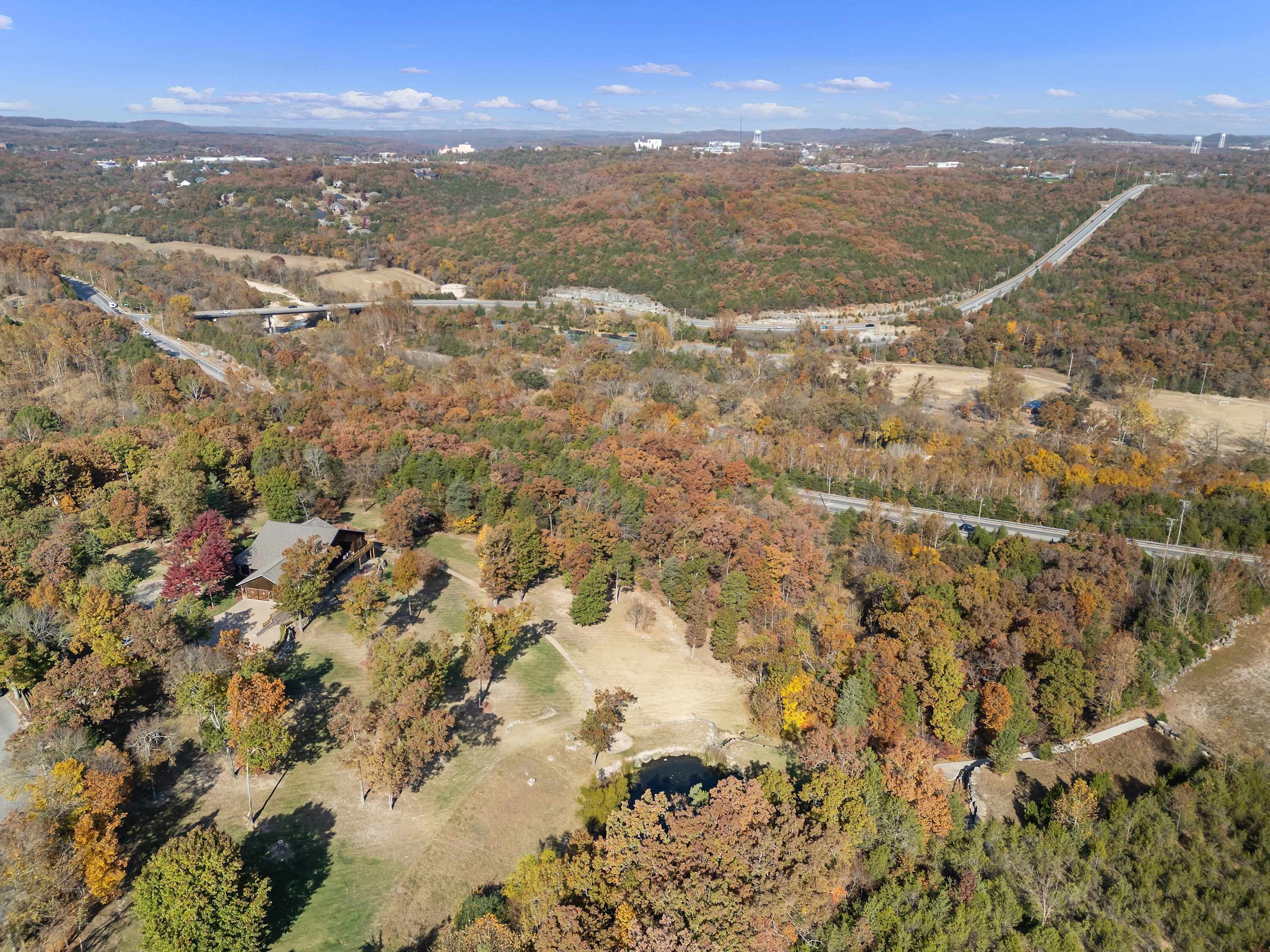 An aerial view of a forested area with a road and a building.