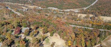 An aerial view of a forested area with a road and a building.