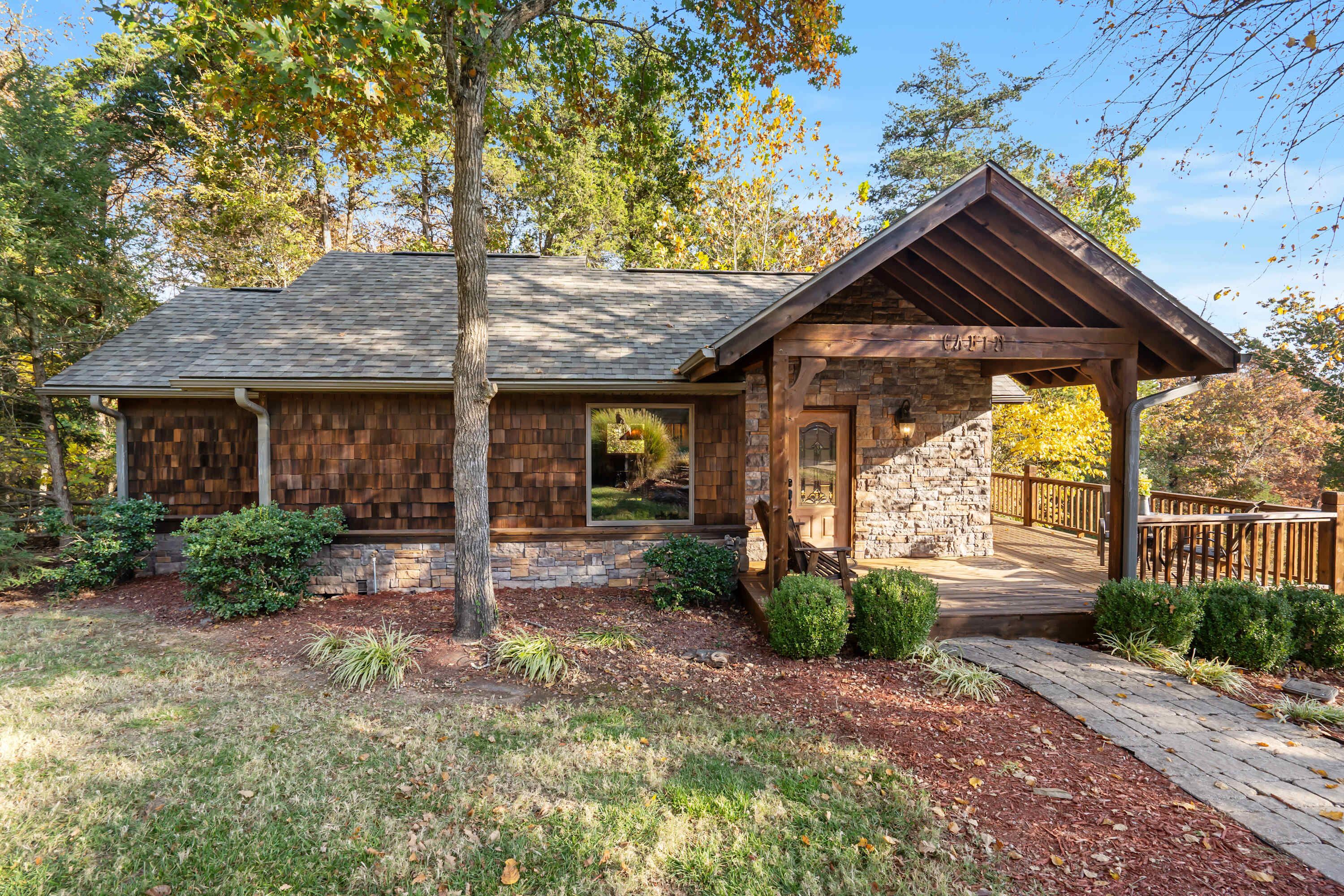 A rustic cabin with a stone exterior, wooden deck, and a covered porch.